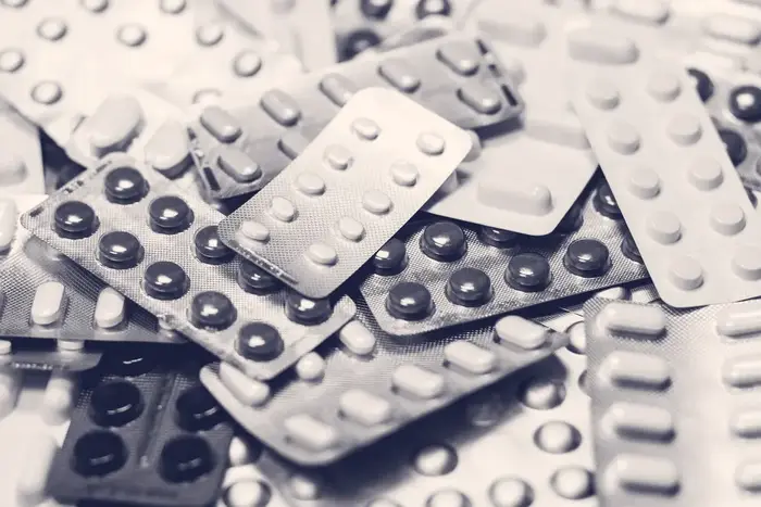 Blister packs of different coloured tablets piled together