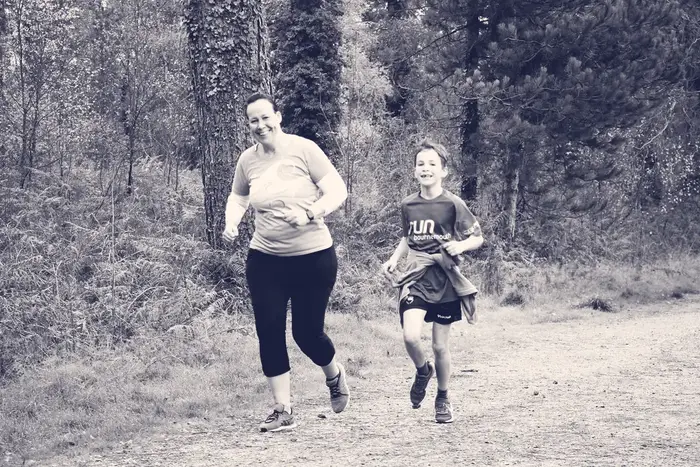 Two people jogging along a woodland path at a community parkrun